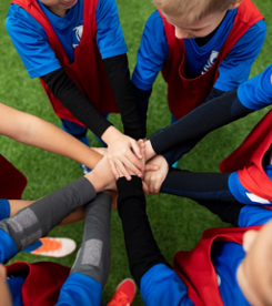 A group of kids in a circle with their hands on top of each other